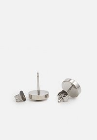 Pendientes de acero inoxidable con diseño circular; cuentan con un acabado liso y un cierre de presión. Un pendiente muestra el vástago.