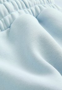 Stof de culoare albastru deschis, cu o textură netedă, având un brâu elastic și un model țesut subtil pe toată suprafața.