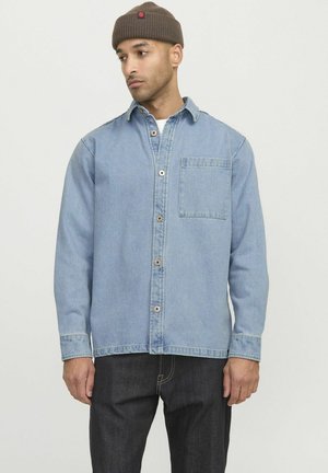 Lichtblauw denim overhemd met een knoopsluiting, kraag en borstzak. Lange mouwen met manchetten, gecombineerd met donkere denim broek.