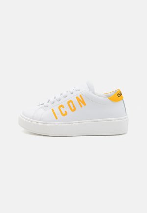 Baltas ādas sneakers ar noapaļotu purngalu, dzeltenu "ICON" tekstu sānos un dzeltenu papēža akcentu. Strukturēta balta gumijas zole.