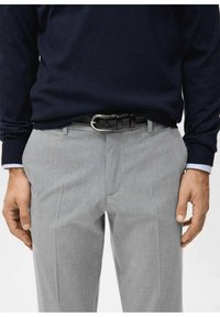 Gray trousers with a smooth texture, featuring a flat front and belt loops. Paired with a navy sweater, showcasing a classic fit. Black leather belt.