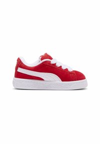 Adidași roșii din suede cu șireturi albe și o linie albă pe lateral. Au o talpă groasă din cauciuc alb cu detalii texturate.