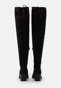 Stivali alti in suede nero con punta arrotondata, finitura texturizzata, dettaglio con lacci sul retro e tacco impilato.