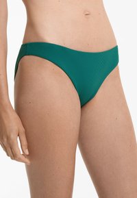 Gröna bikinitrosor gjorda av texturerad tyg, med en sömlös design, låg midja och släta kanter för komfort.