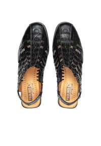 Chaussures en cuir noir avec un design tissé, talon ouvert, et une semelle intérieure de couleur brun clair, présentant des coutures décoratives et une fermeture à boucle.