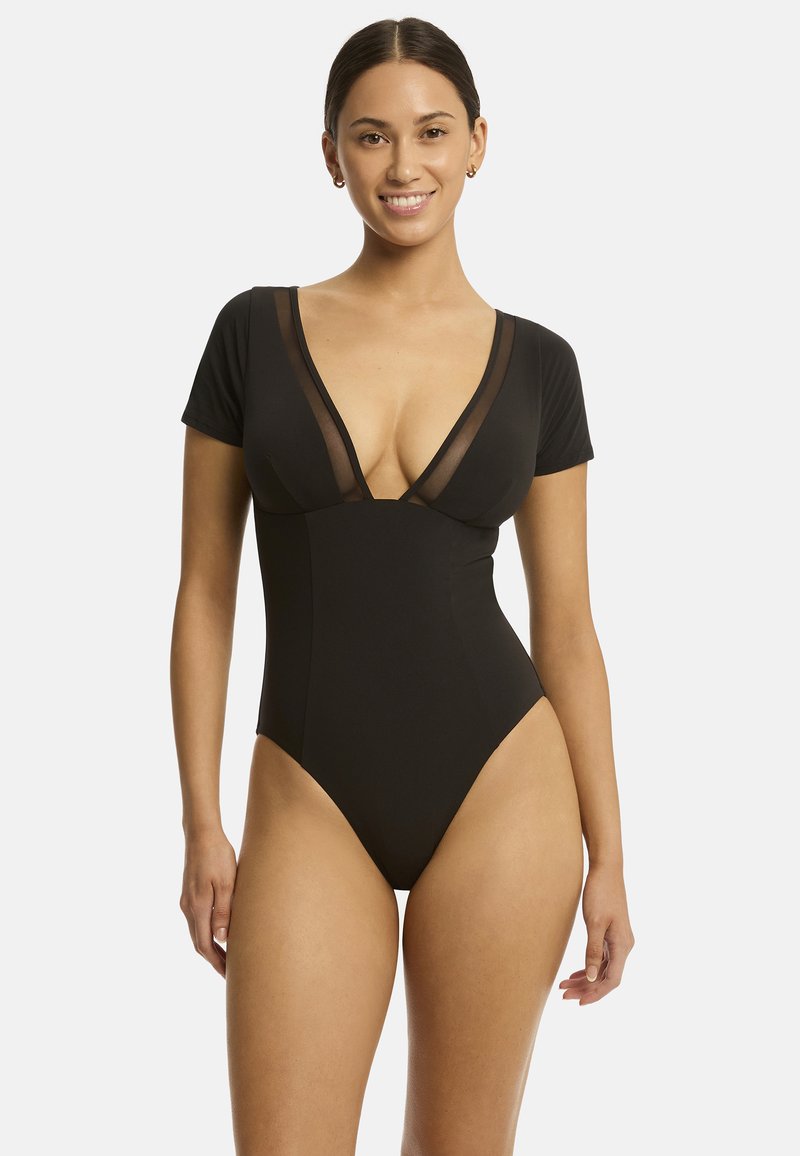 Costume da bagno intero nero con maniche corte, scollatura a V profonda, pannelli in rete e aperture elevate per le gambe. Tessuto liscio e design aderente.
