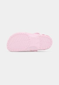 Ροζ Crocs με υφή στη σόλα που διαθέτει βαθιές αυλακώσεις και λουράκι στο πίσω μέρος, κατασκευασμένα από ελαφρύ και ανθεκτικό υλικό.