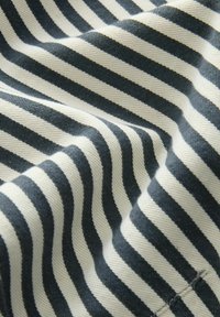 Schwarz-weiß gestreifter Stoff mit sichtbarer Textur und dezenten Falten, die ein wellenförmiges Muster erzeugen.