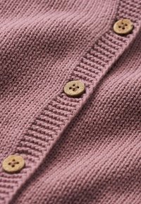 Pletený cardigan v měkké, tlumené růžové barvě s texturovaným žebrováním a čtyřmi dřevěnými knoflíky se vzorem květiny.
