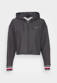 Sudadera corta en tejido gris oscuro, con cremallera completa, capucha ajustable con cordón y acentos de puños a rayas en rojo y blanco.