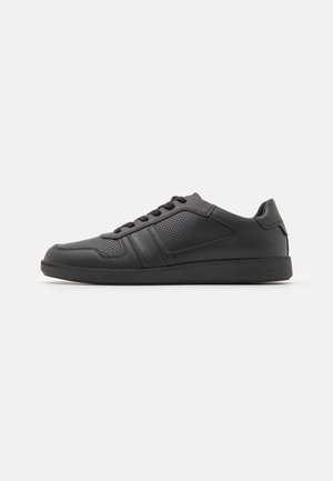 Sneaker sportive nere realizzate in materiale sintetico liscio con accenti perforati, lacci piatti e suola in gomma.