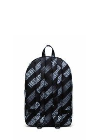 Sac à dos noir avec lettrage blanc en diagonale, texture rembourrée et bretelles ajustables. Comprend une poignée supérieure et deux boucles latérales.