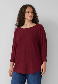 Bordeauxfarbenes, leichtes Strickoberteil mit weitem Ausschnitt, Dreiviertelärmeln und abgerundetem Saum. Bietet eine lockere Passform und weiche Textur.