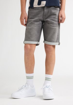 Pantaloni scurți din denim gri, cu tivuri rulotate, asortați cu adidași albi și șosete în dungi. Materialul are o textură fină și o ușoară decolorare.