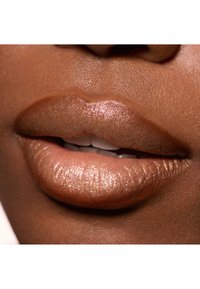 Glansede brune læber med en subtil glimmer, tekstureret med fine linjer. Nuancen skifter fra medium til lys brun, hvilket afslører naturlige konturer.