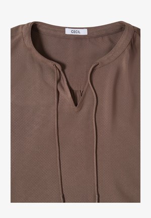 Ruskea paita, jossa on hienovarainen pistekuvio, pyöreä pääntie edessä olevaan halkioon asti, ja pitkät nyörit CECIL-merkin kohdalta alaspäin.