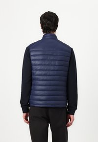 Marineblauwe mouwloze puffervest met een hoge kraag, horizontaal gequilt ontwerp en een gladde, glanzende textuur. Strakke snit met zijnaad.