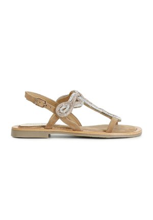Tan suede -materiaalista valmistetut helmivöiset sandaalit, joissa on kimalteleva, solmittu hopeakoriste. Säädettävä nilkkaremmi ja litteä pohja mukavuutta varten.