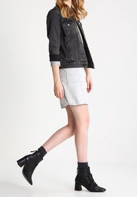 Svart denimjacka med grå ärmslut, tillsammans med en grå klänning. Svarta ankelboots med sammangjort detalj fulländar looken.