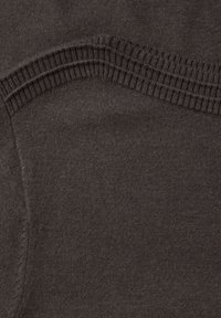 Tissu brun foncé présentant une texture lisse avec une bande côtelée le long du bord, créant un contraste dans les détails de surface.