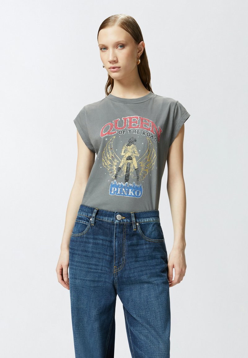 T-shirt grigia con grafica "QUEEN OF THE ROAD" in rosso e oro, maniche corte. Abbinata a jeans in denim blu scuro a vita alta.