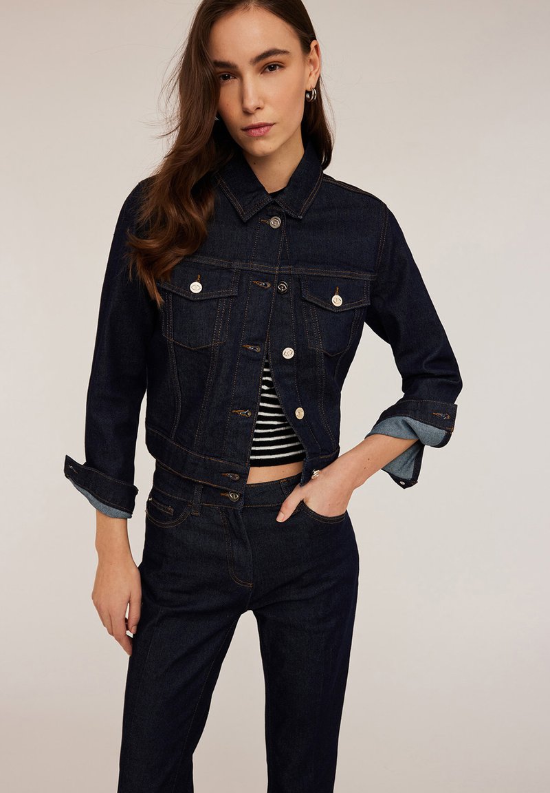 Donker denim cropped jack met een knoopsluiting, twee borstzakken en opgerolde mouwen. Kenmerken zijn contrasterende stiksels en een getailleerd ontwerp.