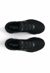Baskets de sport noires avec une tige en maillage texturé, des accents réfléchissants et des lacets élastiques. Comprend un logo en relief et une semelle intérieure rembourrée.