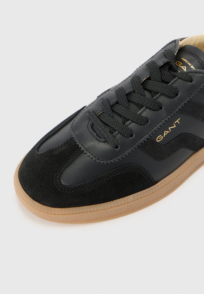 Sneaker neri in pelle e suede, con punta rotonda, lacci testurizzati, suola in gomma e discreto branding dorato.