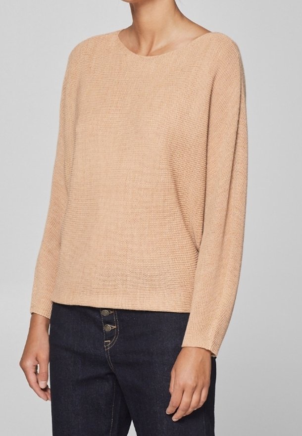 Lichtbeige gebreide trui met een boothals, lange mouwen en een losse pasvorm. De textuur is licht geribbeld, wat goed combineert met donkere spijkerbroeken.