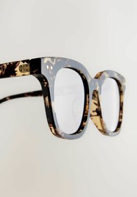Ochelari cu un model țestoasă, având un cadru gros, lucios, de culoare neagră, cu lentile pătrate și curbe moi, un design ușor și accente metalice.