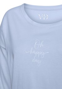 Ljusblå bomullsskjorta med rundad halsringning, prydd med vit text i manusstil "Oh happy day" i mitten. Mjuk textur, avslappnad design.