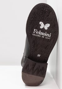 Semelle d'une botte noire montrant le logo papillon, le texte "Telmini FALLING IN LOVE" et la taille 37 marquée sur une semelle en caoutchouc texturée.