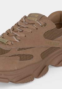 Близък план на кафяв маратонка Steve Madden с панели от велур и мрежа, връзки с шарки и дебела текстурирана подметка.