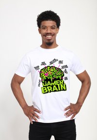 Bílý bavlněný tričko s velkým grafickým designem mozku v zelené a růžové, doplněné o různé textové prvky související se hrami v černé a zelené barvě.