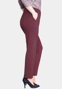 Bordeauxrode broek met een gladde textuur, zijzakken en een rechte pijpdesign. Gepaard met zwarte hoge hakken.