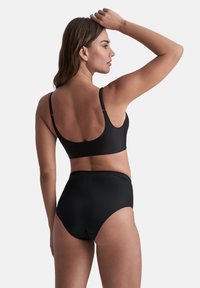 Reggiseno sportivo nero con spalline regolabili e pantaloni a vita alta abbinati. Texture liscia e design semplice, adatto per l'abbigliamento sportivo.