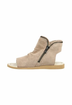 Sandalia de cuña de ante beige perforado con puntera abierta, cremallera lateral y suela de goma plana, mostrada de perfil sobre fondo blanco.