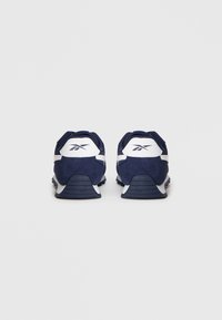 Ein Paar Marineblau-weiße Reebok-Sneaker, von hinten auf einem schlichten hellen Hintergrund gezeigt.