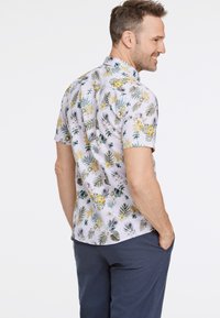 Korte mouwen shirt met een bloem- en bladerenpatroon in geel, groen en blauw op een lichte achtergrond, gemaakt van lichtgewicht stof.