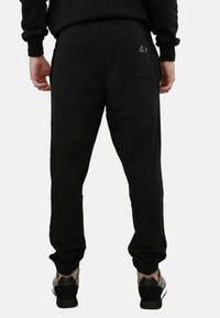 Pantaloni jogger neri con vestibilità rilassata, polsini elasticizzati e una tasca posteriore con logo. Tessuto morbido, realizzati in un tessuto comodo.