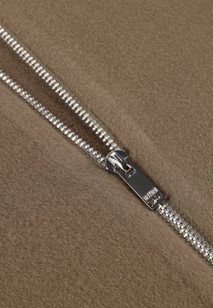 Silberner Metallreißverschluss teilweise geöffnet auf strukturiertem braunem Stoff, der ineinandergreifende Zähne und einen glatten Ziehgriff zeigt.