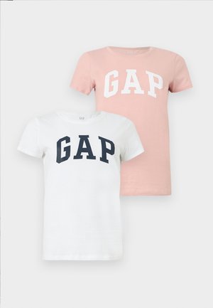 Δύο κοντομάνικα t-shirts της GAP, το ένα λευκό με μπλε γράμματα, το άλλο ροζ με λευκά γράμματα, παρουσιασμένα σε απλό φόντο.
