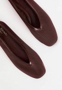 Burgundy ballerinas med fyrkantig tå, tillverkade av texturerat tyg, med en slät läderkant längs öppningen och en enkel, strömlinjeformad design.