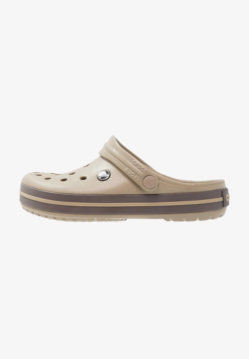 Sabots Crocs beige à enfiler avec des trous de ventilation, sangle arrière ajustable et rayures de semelle brun foncé.