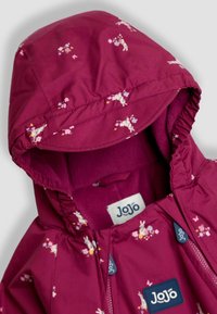 Chaqueta con capucha fucsia y patrón floral, que cuenta con un forro interior suave, bordes elásticos y una etiqueta en el interior. Cierre con cremallera.