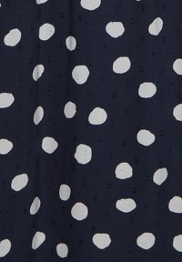 Tissu sombre avec des pois blancs irréguliers, texture légèrement froissée et de subtils petits détails en relief partout.
