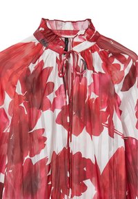 Sheer blouse with a high neckline and tie detail, featuring a floral pattern in red and white, with pleated texture and light, flowing fabric.