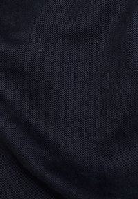 Mörkblå denimtyg med ett subtilt diagonalt vävmönster, slät struktur och vikta kanter, som visar en enhetlig färg med minimal variation.