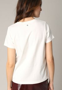 Witte T-shirt met korte mouwen, voorzien van een ronde halslijn en een klein logo detail op de achterkant. Zacht, soepel materiaal met een casual fit.