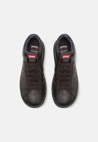 Czarne skórzane sneakersy z tkaninowym wykończeniem, zaokrąglony czubek, sześć oczek do sznurowania i czerwone logo marki. Teksturowana powierzchnia oraz wyściełane wsparcie kostki.